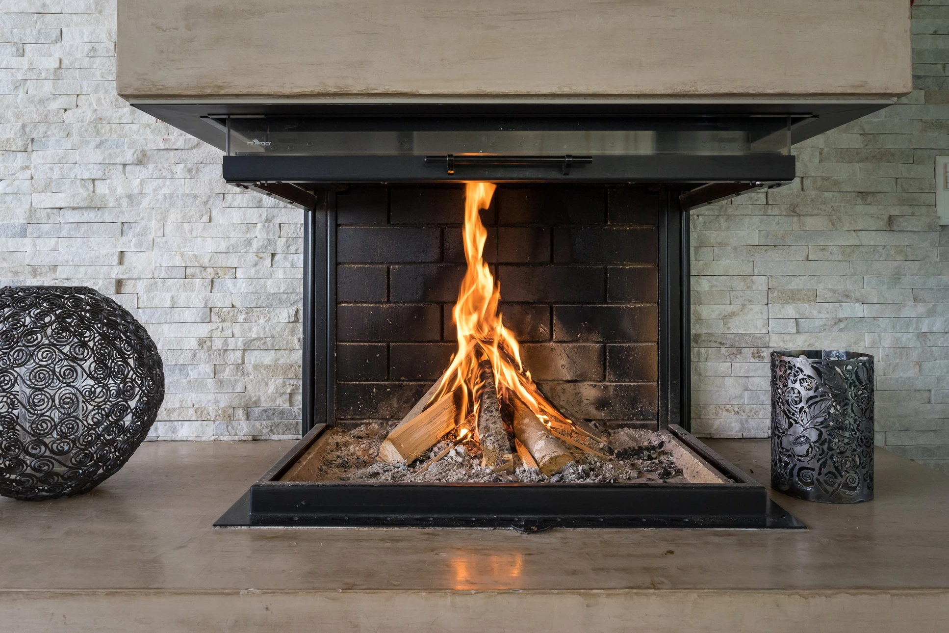 Intérieur moderne avec cheminée à foyer ouvert en fonctionnement, flammes vives sur bûches de bois