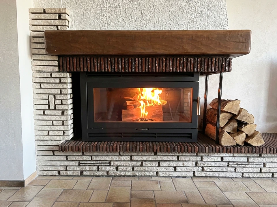 Cheminée traditionnelle en brique avec feu de bois actif, andirons en fer forgé supportant bûches enflammées