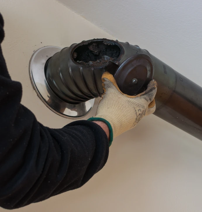 Un technicien spécialisé en vêtements de travail effectuant une intervention d'entretien ou de maintenance sur un poêle à bois ou un insert de cheminée, visible à l'intérieur d'une maison. Le technicien doit être en train de travailler sur l'appareil avec des outils appropriés, montrant une expertise et une connaissance approfondie du système. L'environnement doit être un intérieur domestique réaliste avec le poêle ou la cheminée clairement visible.
