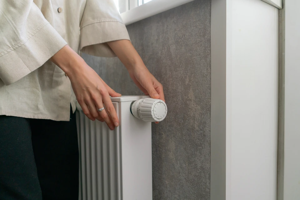 Photographie d'un intérieur contemporain et chaleureux montrant un radiateur Solaris en verre fixé au mur, dans une pièce de vie moderne avec mobilier épuré. La pièce est éclairée d'une lumière douce provenant du radiateur, créant une ambiance de confort thermique. Le radiateur doit être clairement visible et le point focal de la composition, dans un cadre intérieur sophistiqué et apaisant qui évoque le concept de "cocon chaleureux".